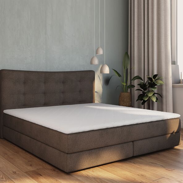 Komfortschaum-Matratzentopper Basis in der Größe 180 x 200 cm, freigestellt auf weißem Hintergrund, leicht gewellt, um die Textur des Materials zu zeigen.