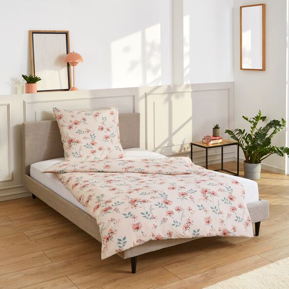 Set von Bettwäsche mit floralem Muster ausgebreitet auf einem Bett.