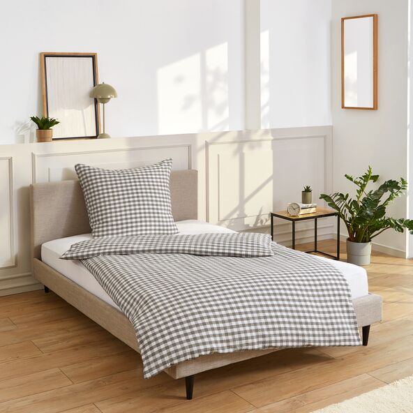 Set von Bettwäsche mit kariertem Muster ausgebreitet auf einem Bett.
