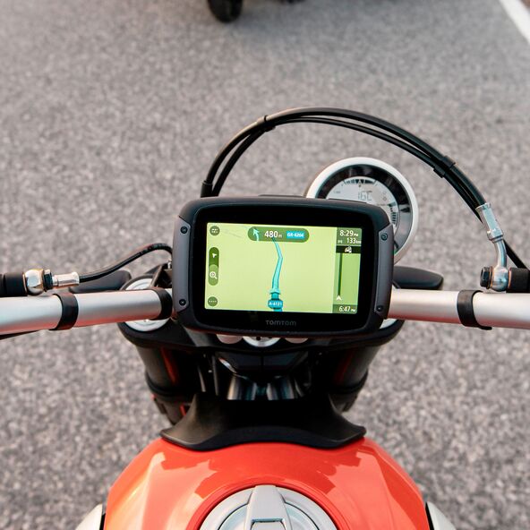Motorrad-Navi mit Touchscreen auf Motorradlenker montiert. Das Display zeigt eine Kartenansicht.