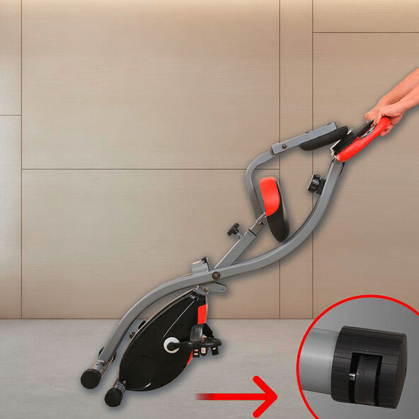 Zusammengeklappter Heimtrainer F-Bike Curved mit gebogener Rahmenform in Schwarz und Grau vor neutralem Hintergrund, teilweise mit Produktlogo.