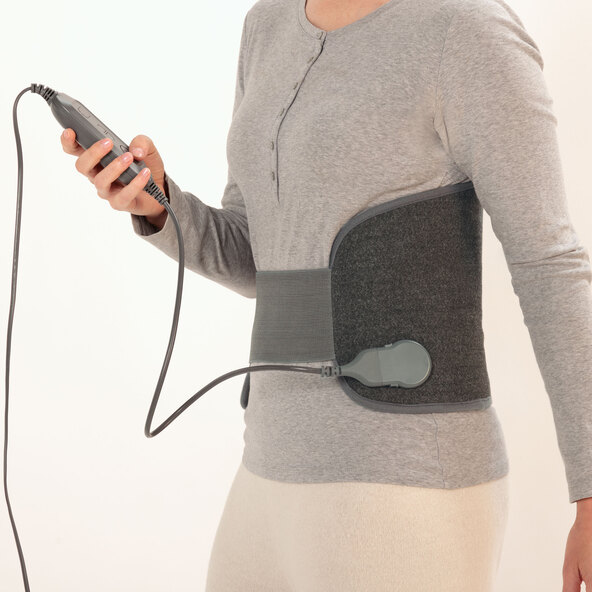 Lendenwärmer aus Textil mit Heizkabel, vor hellem Hintergrund, perspektivisch leicht von oben fotografiert. Das Produkt ist mittig platziert und gut ausgeleuchtet.