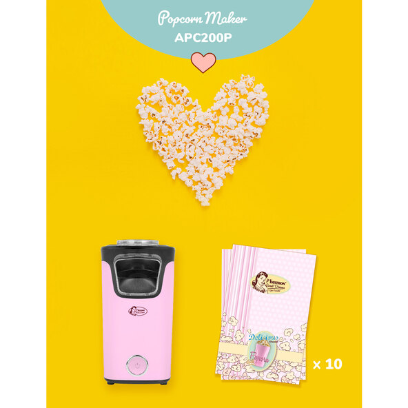 Pinke Popcornmaschine mit transparentem Behälter und schwarzem Sockel. Frisches Popcorn quillt aus dem Gerät.