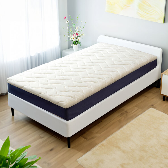 Komfortschaum Topper auf einem Bett mit weißer Bettwäsche, leicht erhöht, für verbesserte Schlafqualität.