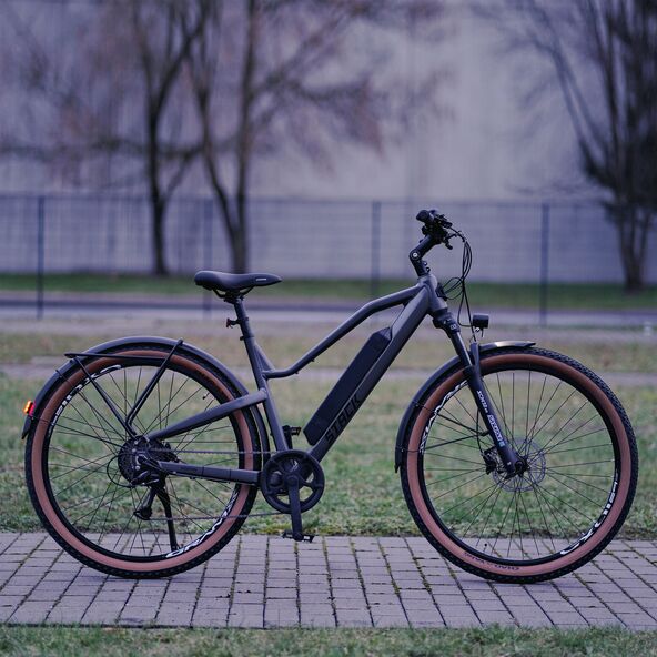 Dunkelblaues E-Mountainbike mit 29-Zoll-Reifen, Federgabel und sportlicher Rahmengeometrie, abgebildet vor hellem Hintergrund.