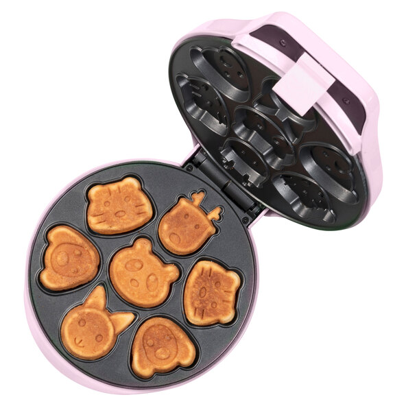Pinkfarbener Mini Cookie Maker mit Antihaftbeschichtung und Griffmulden. Mehrere frisch gebackene, kleine Kekse liegen darauf und daneben.