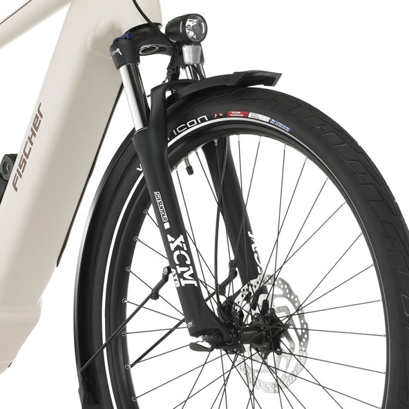Ein silbergraues E-Bike Trekking mit Trapezrahmen, Gepäckträger, Schutzblechen und gefederter Gabel steht seitlich auf ebenem Grund.