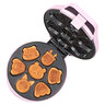 Pinkfarbener Mini Cookie Maker mit Antihaftbeschichtung und Griffmulden. Mehrere frisch gebackene, kleine Kekse liegen darauf und daneben.