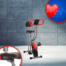 Zusammengeklappter Heimtrainer F-Bike Curved mit schwarzem Rahmen und roten Akzenten auf hellem Untergrund, Sattel und Display sind erkennbar.