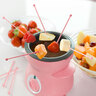 Pinkfarbenes Mini Schoko-Fondue-Set mit Keramikschale, Teelichthalter und zwei Gabeln auf weißem Hintergrund, geeignet für den kleinen Schokoladen-Genuss.