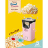 Pinke Popcornmaschine mit transparentem Behälter und schwarzem Sockel. Fertiges Popcorn quillt aus dem oberen Bereich.