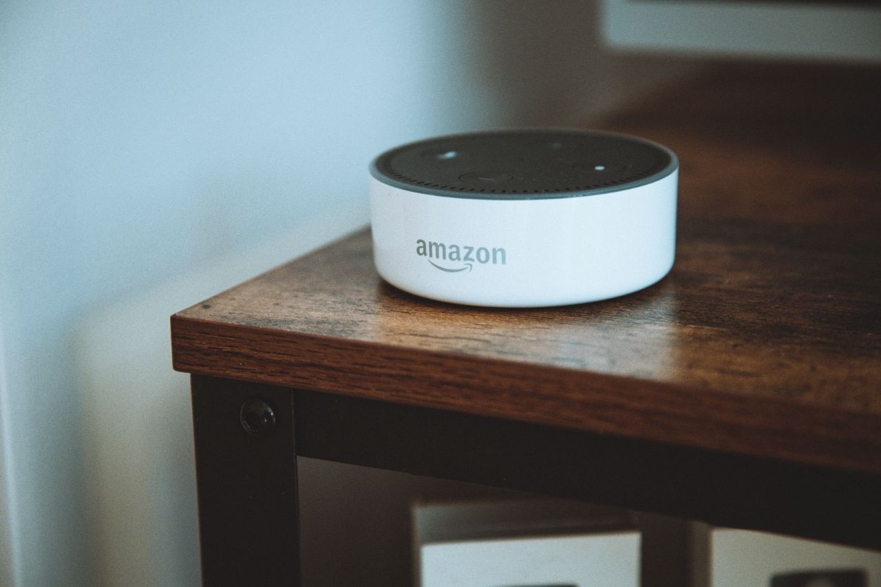 Schwarz-brauner Tisch mit einem weißen Amazon Alexa Echo Dot Lautsprecher darauf