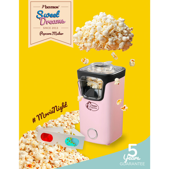 Pinke Popcornmaschine mit transparentem Behälter und schwarzem Sockel. Fertiges Popcorn quillt aus dem oberen Bereich.