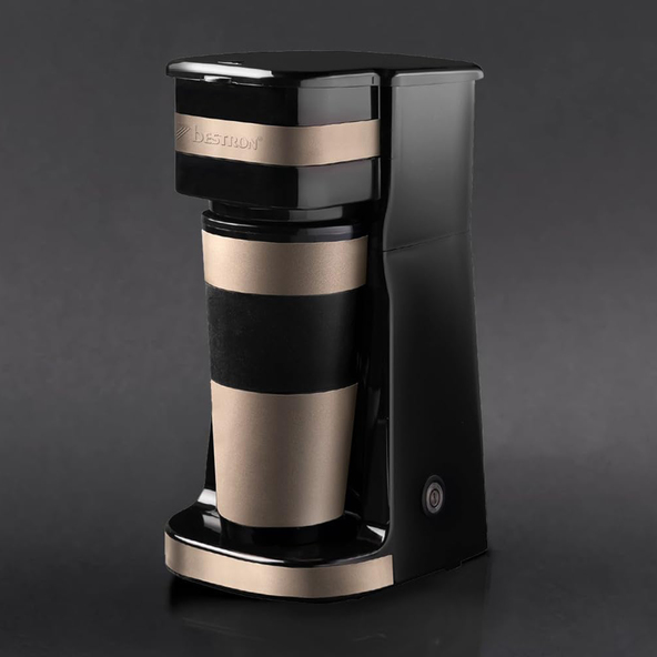 Beige, kompakte Kaffeemaschine mit Thermobecher auf hellem Untergrund. Das Gerät hat ein minimalistisches Design mit klaren Linien und abgerundeten Kanten.