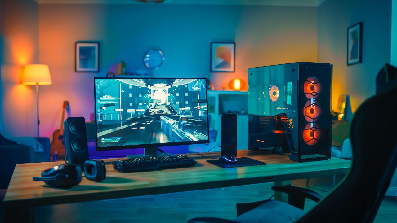 Holz-Schreibtisch mit Gaming-PC, Lautsprechern, Tastatur, Maus, Headset und einem Monitor auf dem ein Shooter-Spiel läuft