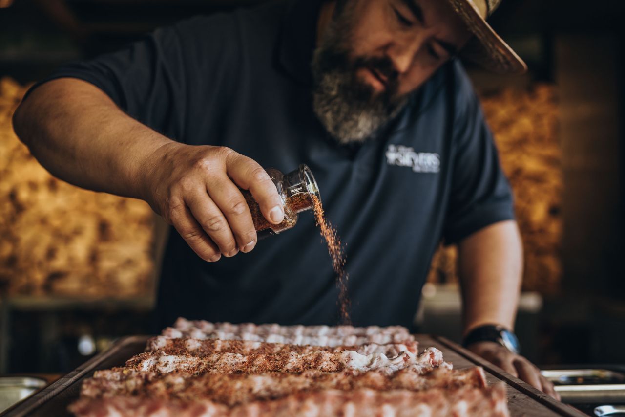Mann streut Gewürz über Spare Ribs.