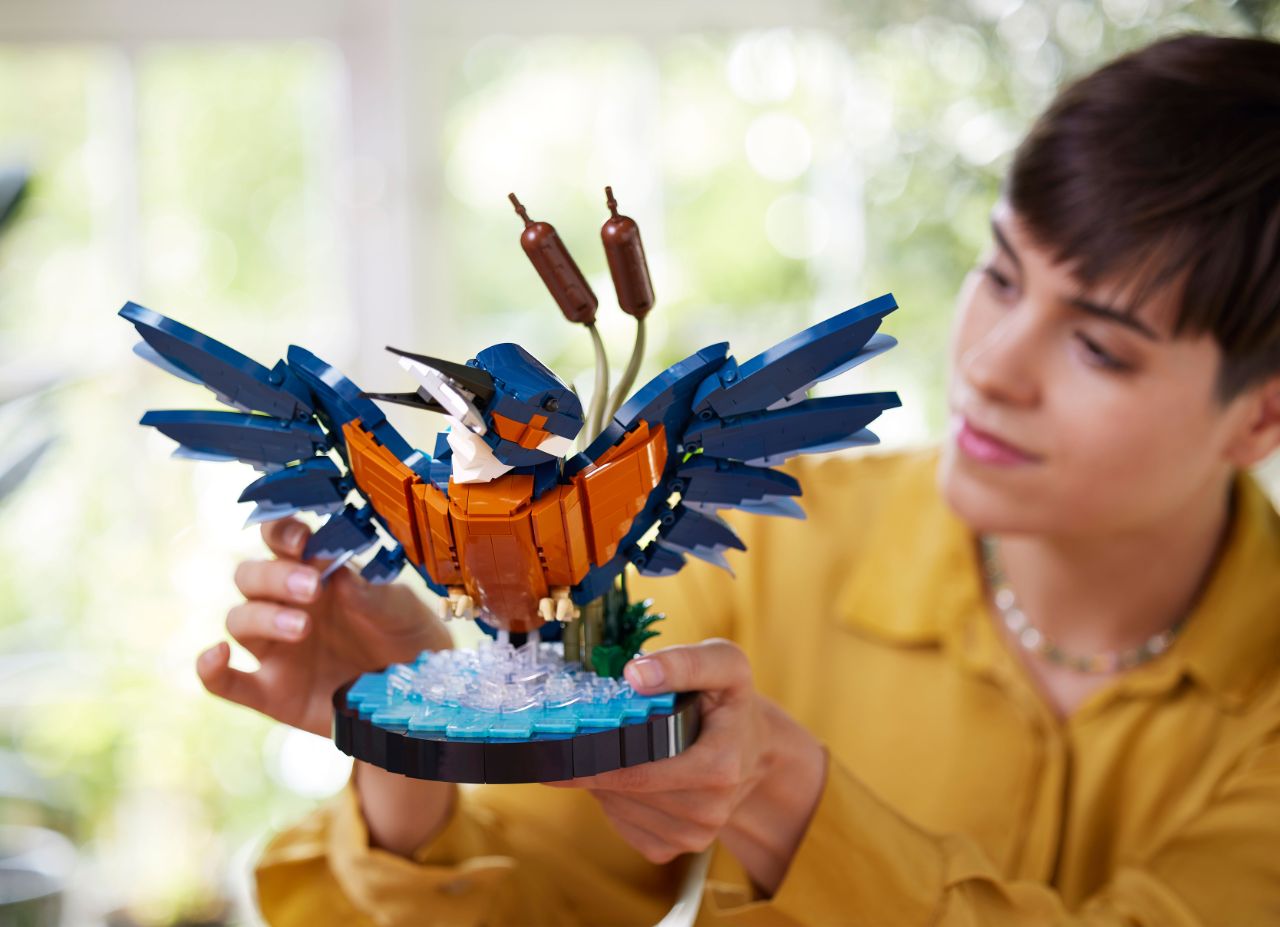 Frau hält einen zusammengebauten LEGO-Eisvogel in der Hand