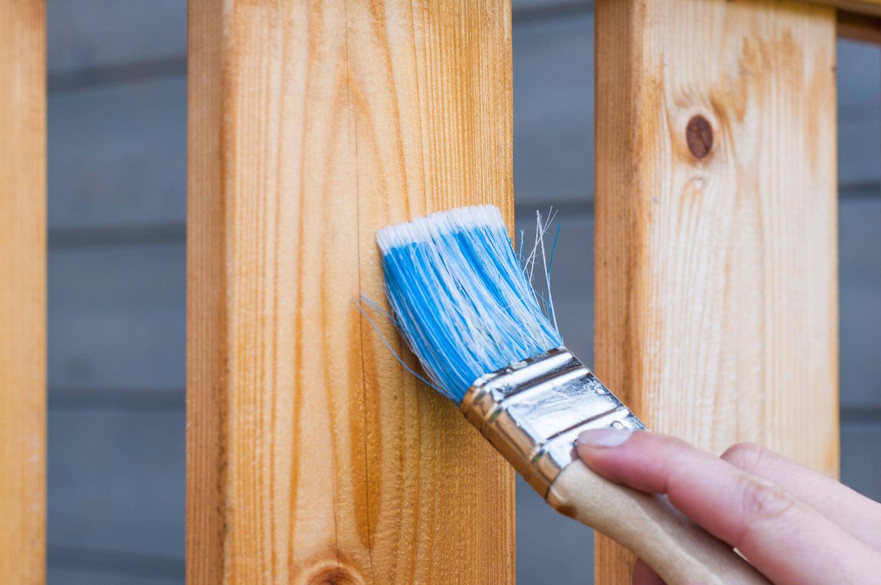 Holzbalken werden mit einem Pinsel aus blauen Borsten lackiert