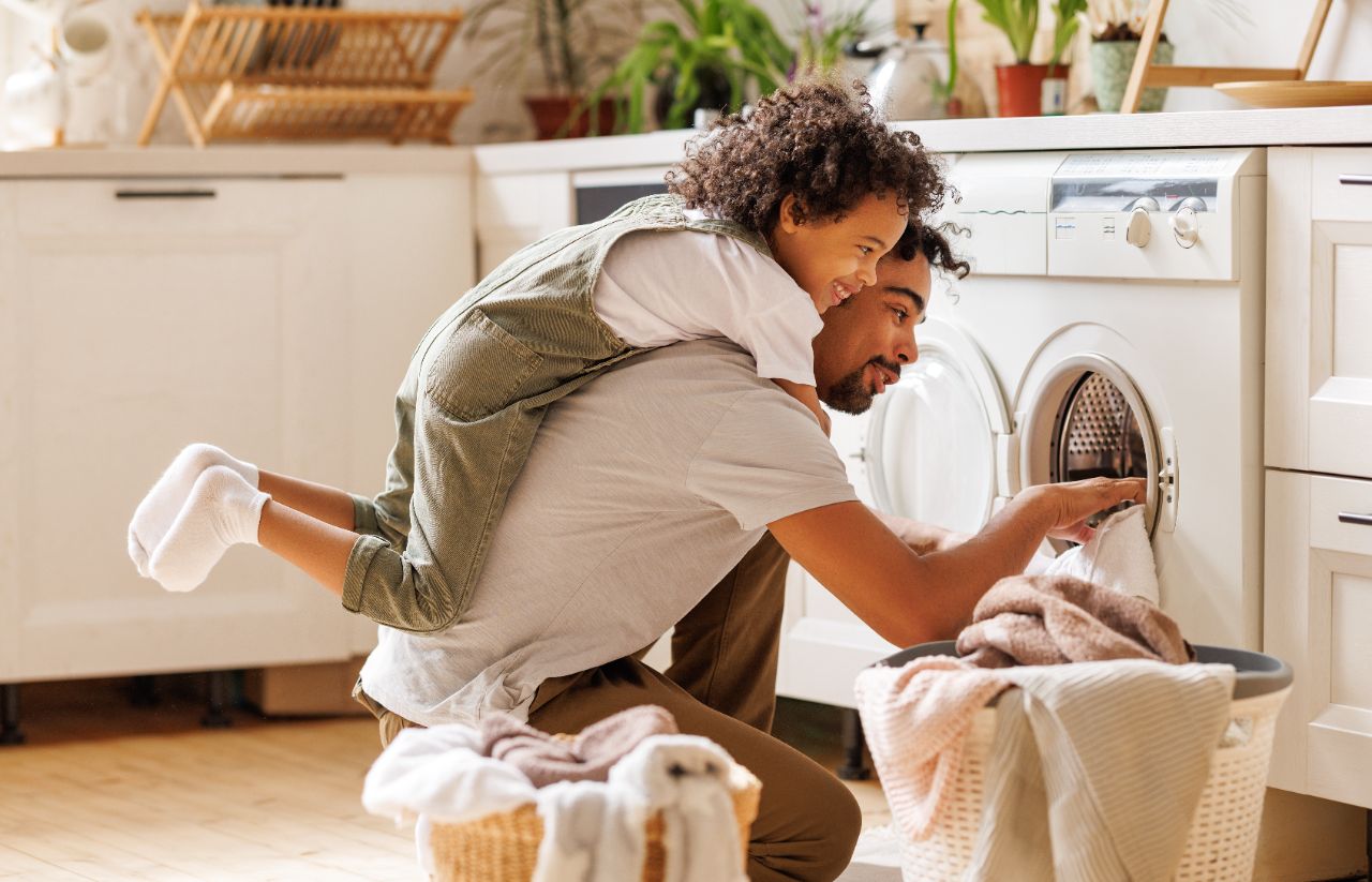 Mann mit Sohn befüllt die Waschmaschine