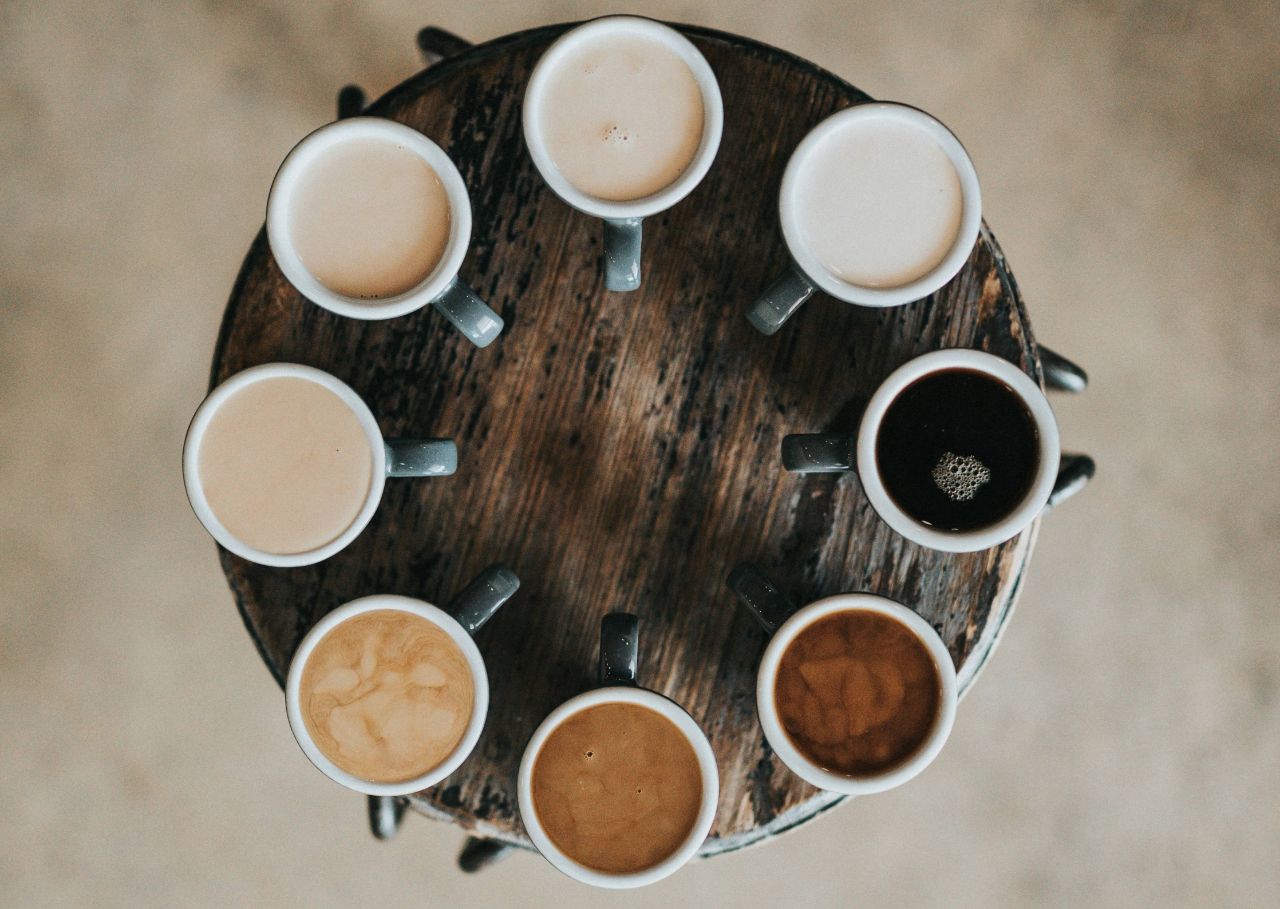 Verschiedene Kaffeetassen mit Barissimo Kaffeevariationen auf einem Tisch im Kreis aufgestellt