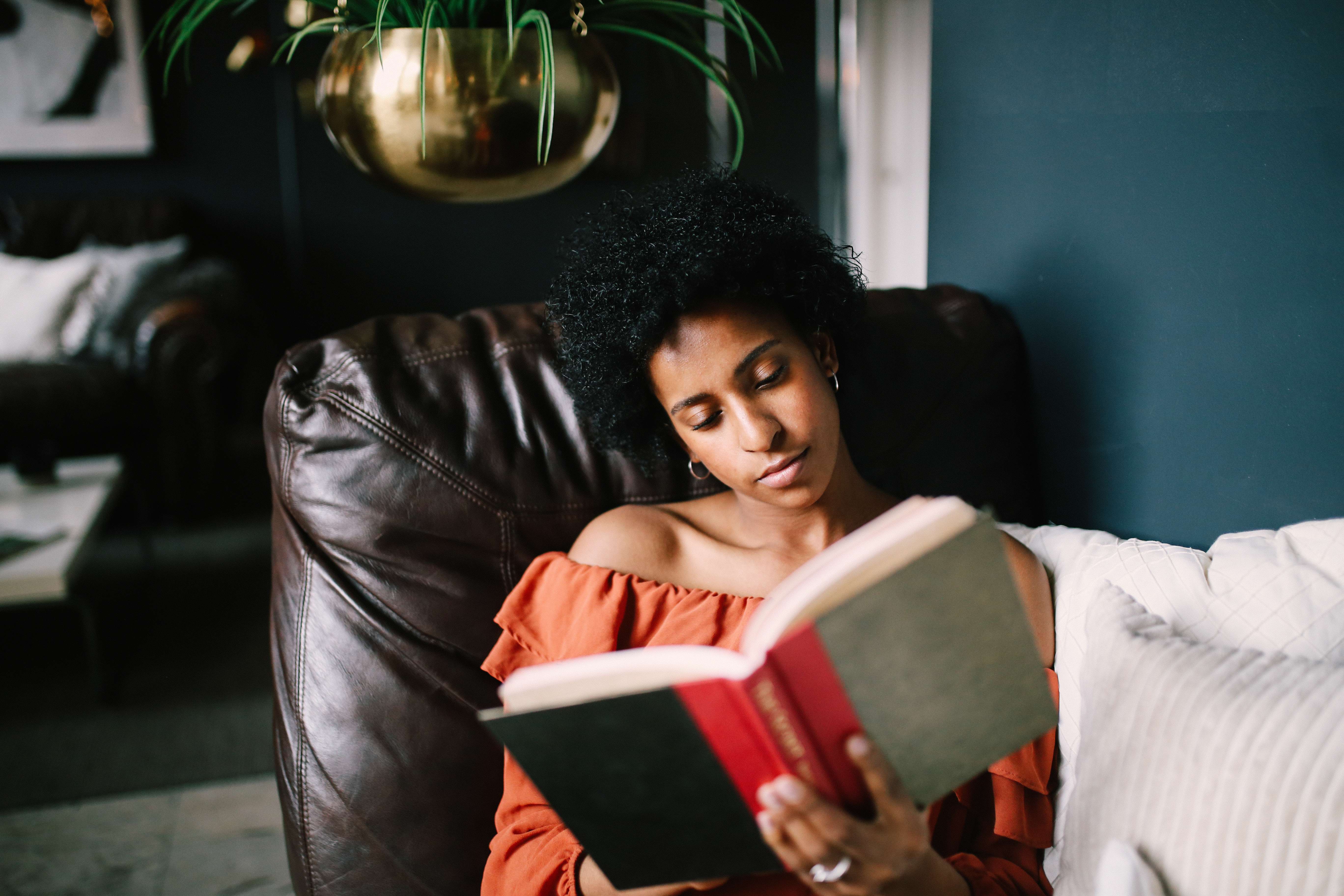 Frau sitzt auf Couch und liest ein Buch