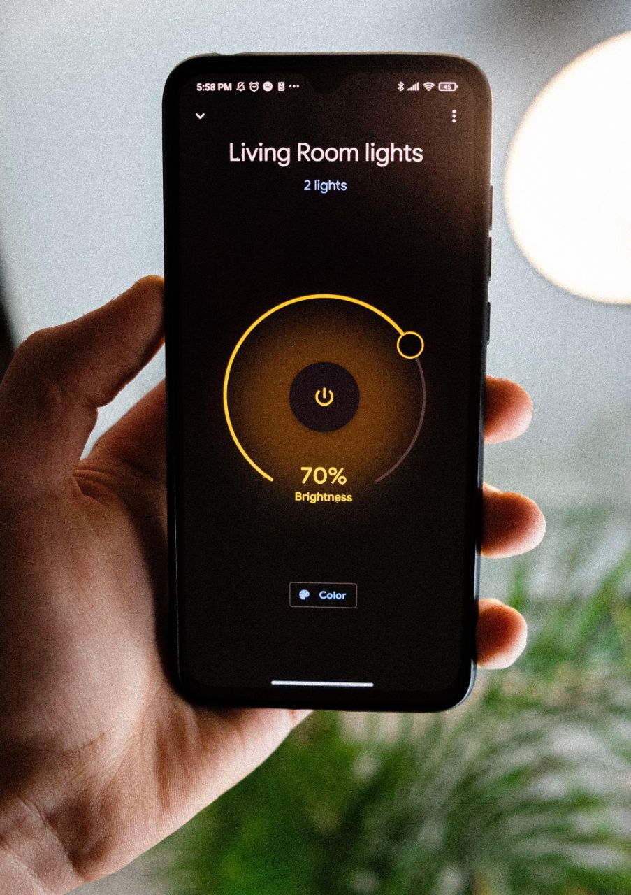 In einer Hand gehaltenes Smartphone mit geöffneter Smart-Home Anwendung zur Steuerung des Lichts