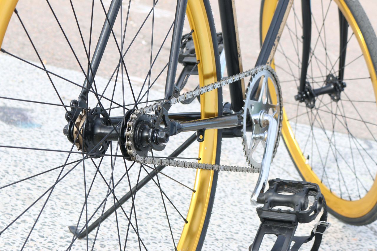 Detailaufnahme der Kette und Speichen eines schwarz-goldenen Fahrrads