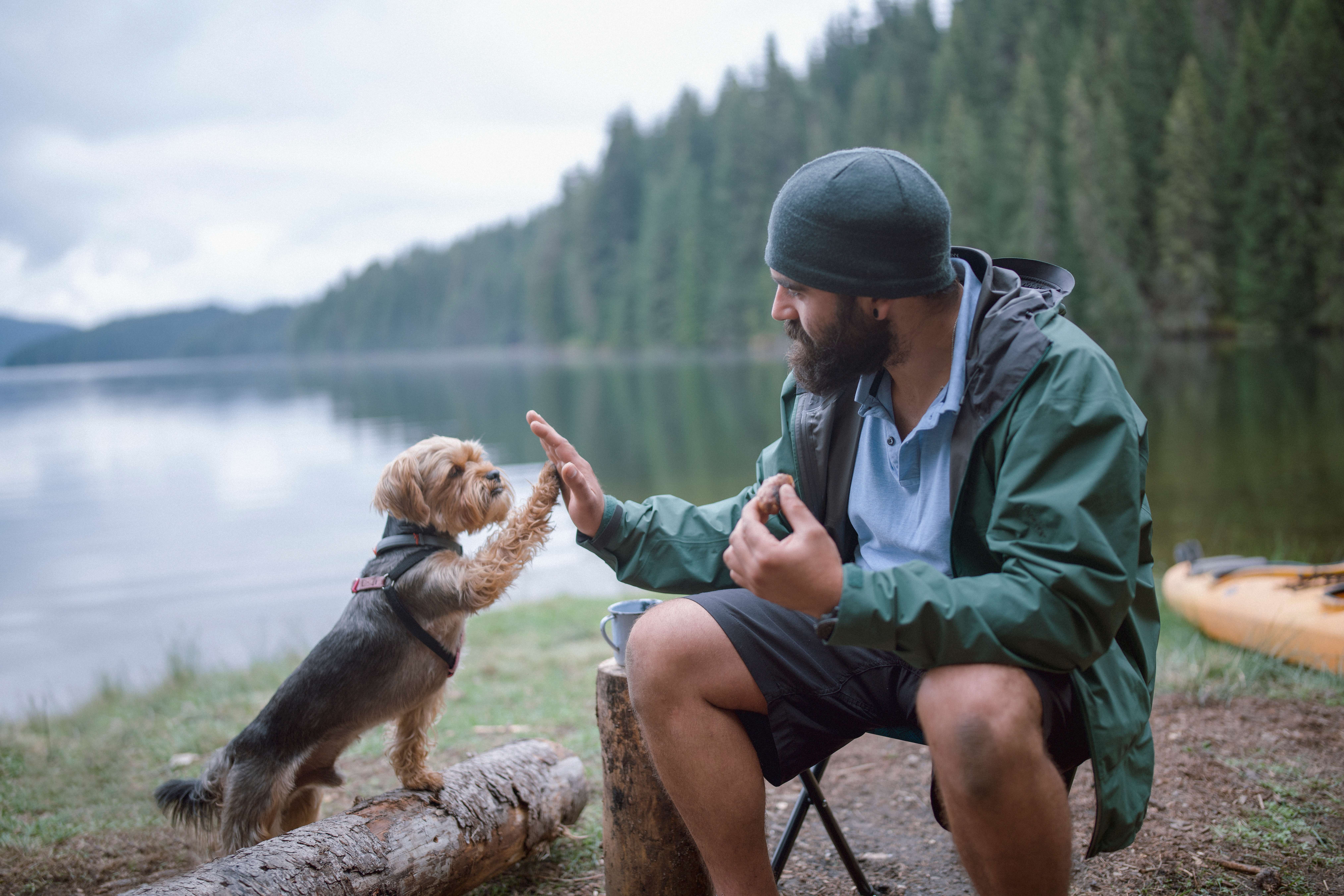 Mann sitzt mit Hund am See