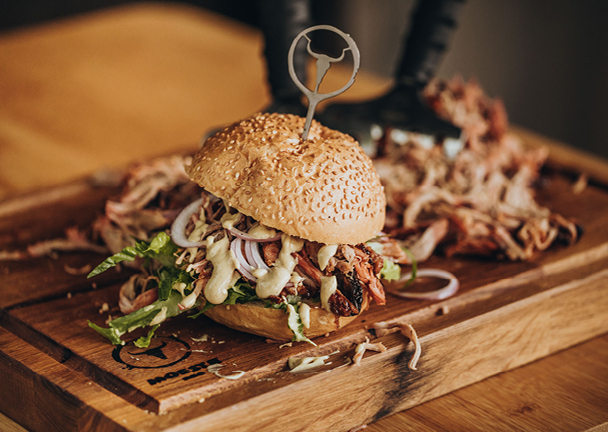 Burger mit Pulled Pork auf Holzschneidebrett.
