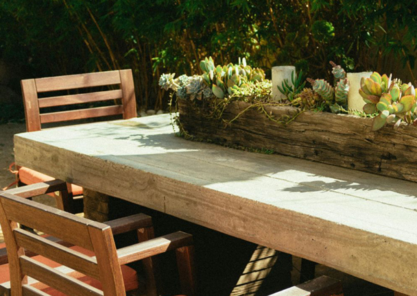 Gartenmöbel aus Holz auf der Terrasse mit Tischdekoration im Holzkasten.