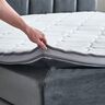 Anthrazitfarbenes Boxspringbett mit großem Kopfteil, bezogen mit Stoff, Liegefläche 180x200 cm, auf Füßen stehend, im Hintergrund helle Wand.