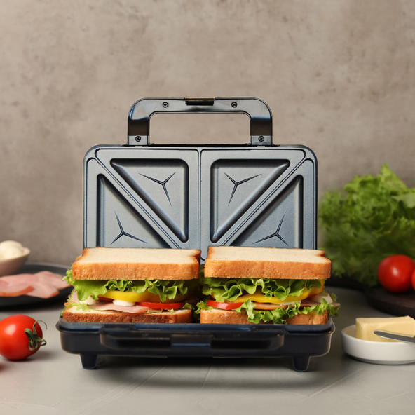 Silberner Sandwichmaker mit geriffelten Heizplatten, geschlossen dargestellt. Zwei Toast-Sandwiches sind leicht erkennbar. Das Gehäuse ist aus Metall.