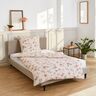 Set von Bettwäsche mit floralem Muster ausgebreitet auf einem Bett.