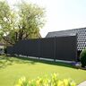 Moderner Sichtschutzzaun in dunklen Farben, der eine grüne Wiese von einem privaten Garten abgrenzt.