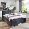 Anthrazitfarbenes Boxspringbett Premium mit gestepptem Kopfteil und hoher Matratze auf einem Untergestell mit Füßen. Das Bett ist auf einem hellen Untergrund fotografiert.