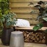 Holzlagerbank Tyr aus Holz mit integriertem Stauraum unter der Sitzfläche, geeignet zur Lagerung von Brennholz, vor einer hellen Wand.