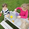Graue Outdoor Kindersitzgruppe Play mit Tisch und vier Hockern auf einer Rasenfläche vor einem Haus.
